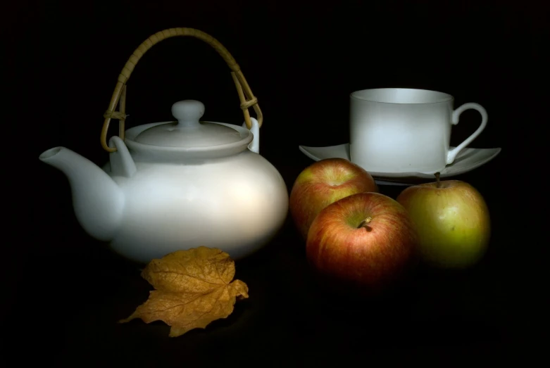 an apple, a teapot and two glasses are sitting next to each other