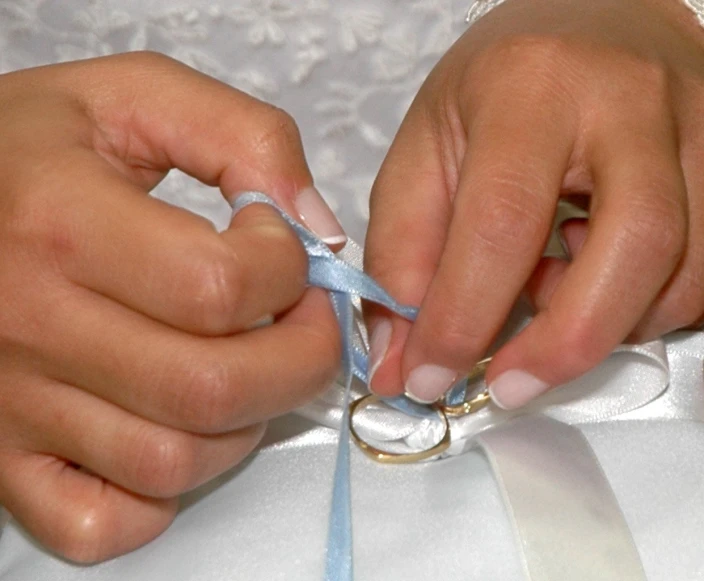 a woman is tying a ring with a blue ribbon