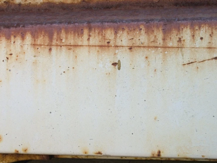 a rusted surface with scratches and a piece of paint