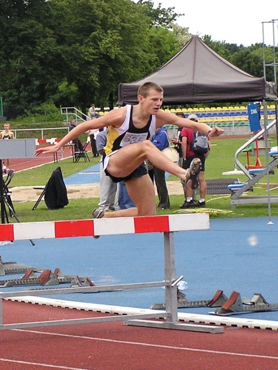 a girl jumping over a hurdle on a blue track