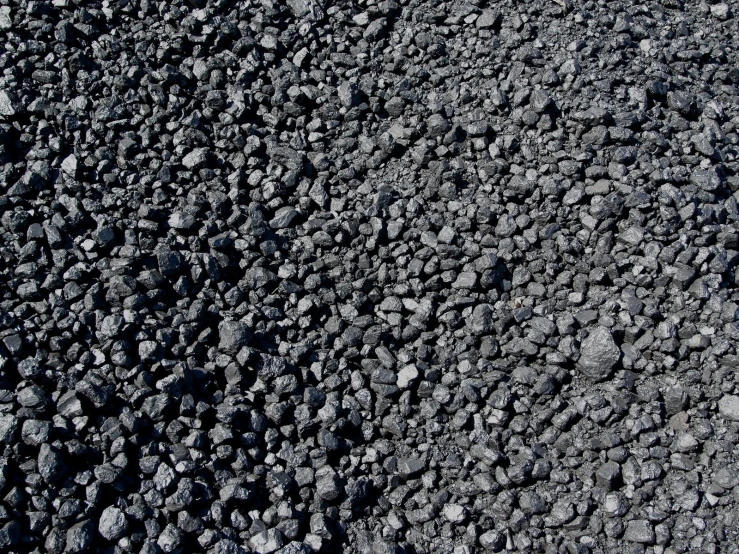 the surface of a black rocky road with black rocks on top