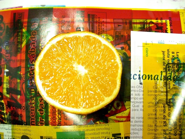 an orange cut in half laying on newspaper