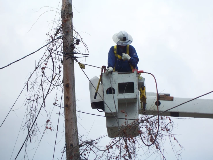 a man on a utility vehicle repairs power lines