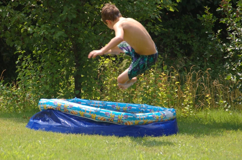 a boy jumps off his trampoline on the grass