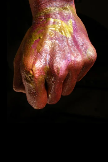a hand that has some pink and yellow paint on it