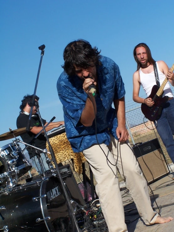 people on a road playing instruments, one man wearing blue with the other man in white