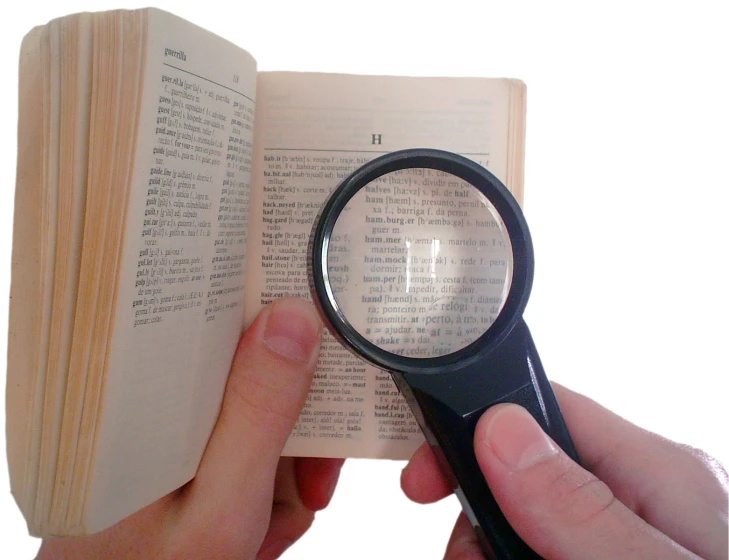hand holding magnifying glass with an open book