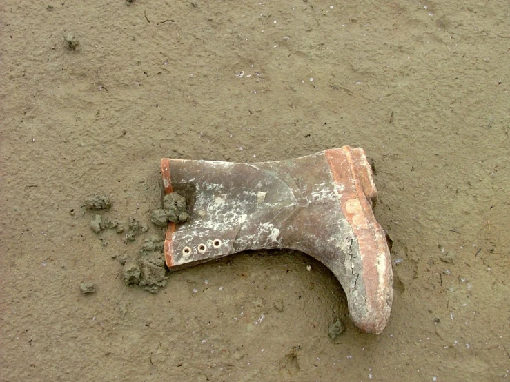 an old dirty and worn metal object that is on dirt ground