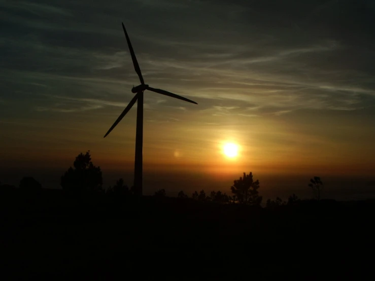 a view of a sunset with two wind mills in the foreground