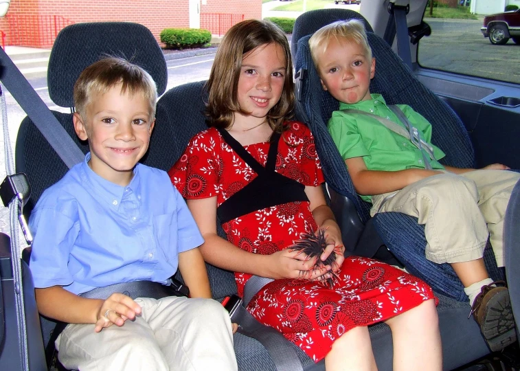 three little s sitting in the front row of a car