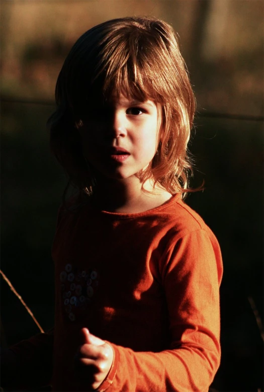 a little girl wearing a red top and posing for the camera