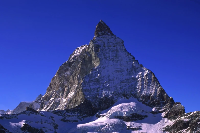 a snow covered mountain top under a blue sky