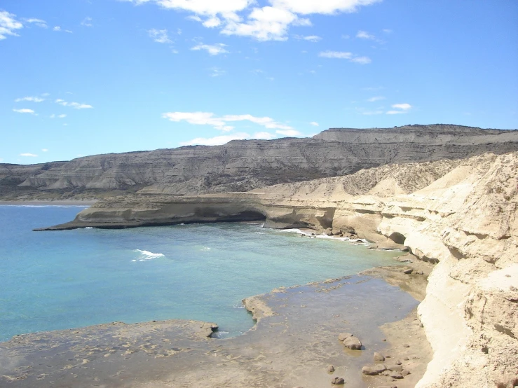 a blue ocean filled with lots of water next to a rocky shore