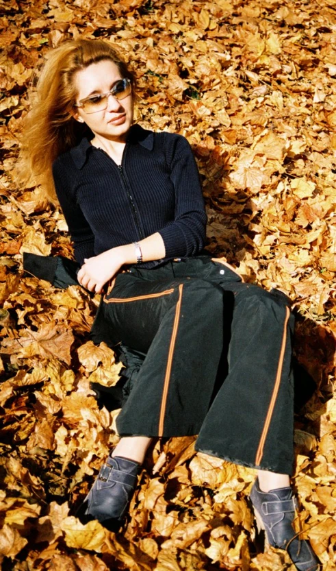 a woman with long hair and sunglasses is lying on the ground with her back to the camera