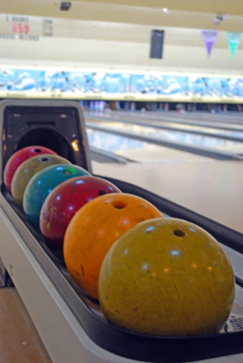 a line of colorful bowling balls sitting on top of a bowling alley