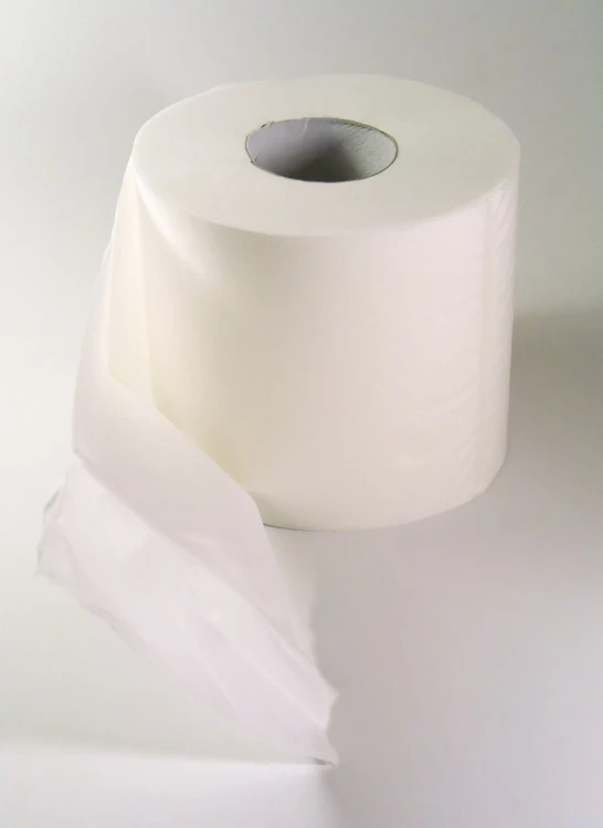 an unopened white toilet paper roll lying on top of the toilet