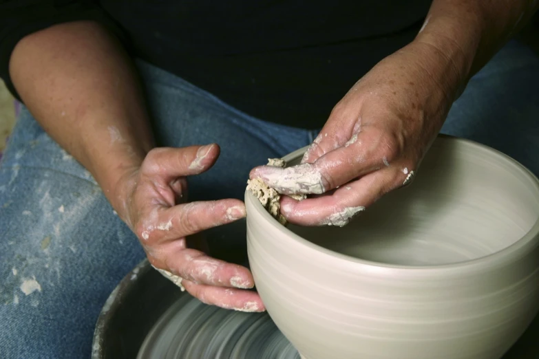 hands in a pottery bowl making clay
