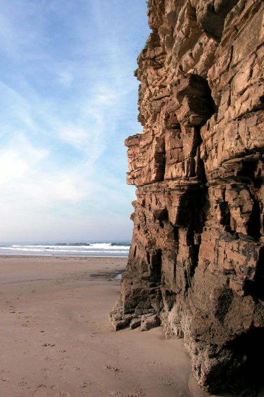 a stone wall sitting on the sand near the water