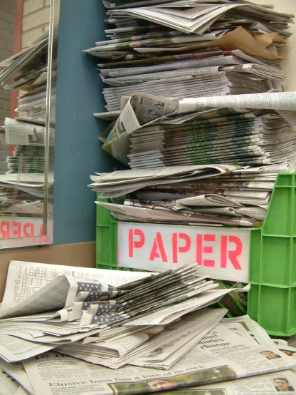stacks of newspapers are stacked on a desk with a sign saying paper