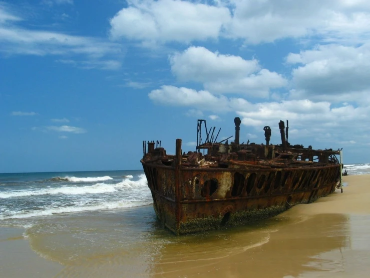 a rusty ship that is laying in the sand
