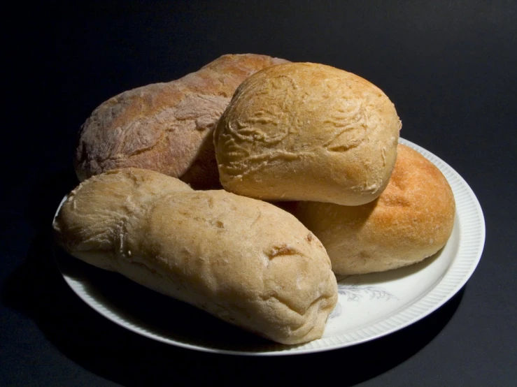 three round breads are sitting on a white plate