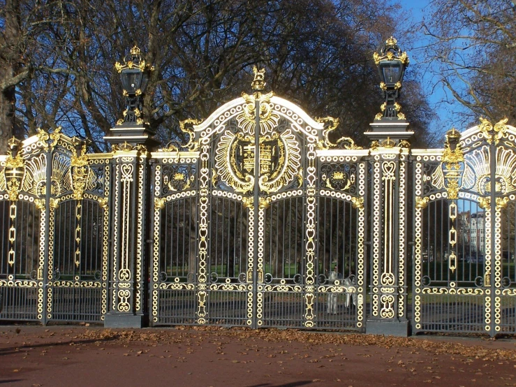 an ornate iron gate with statues and columns is in front of trees