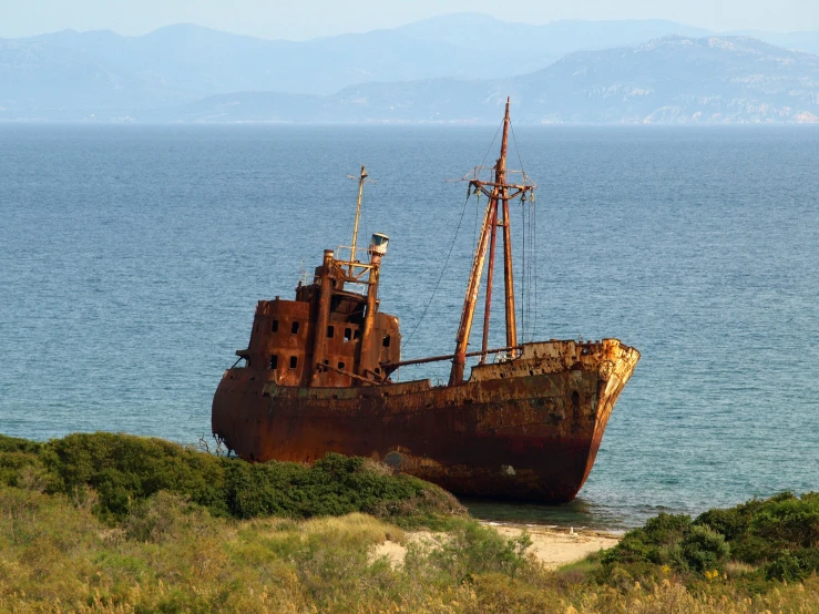 an old rusted ship sits on the shore
