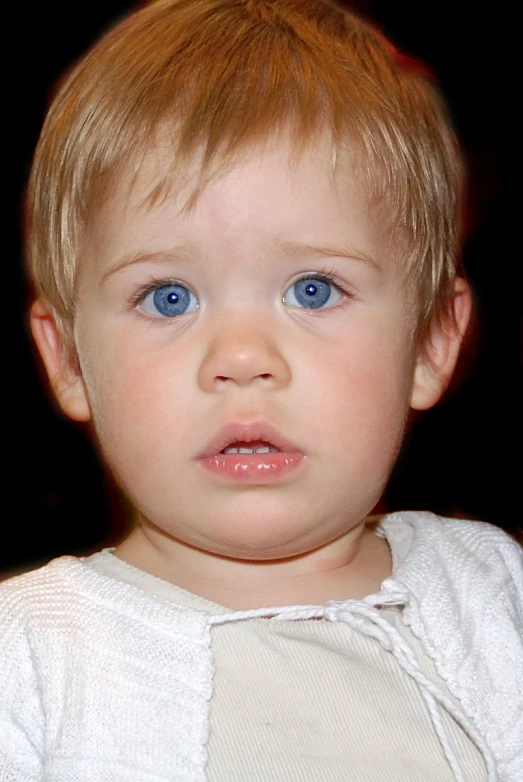 a very cute looking little boy with bright blue eyes