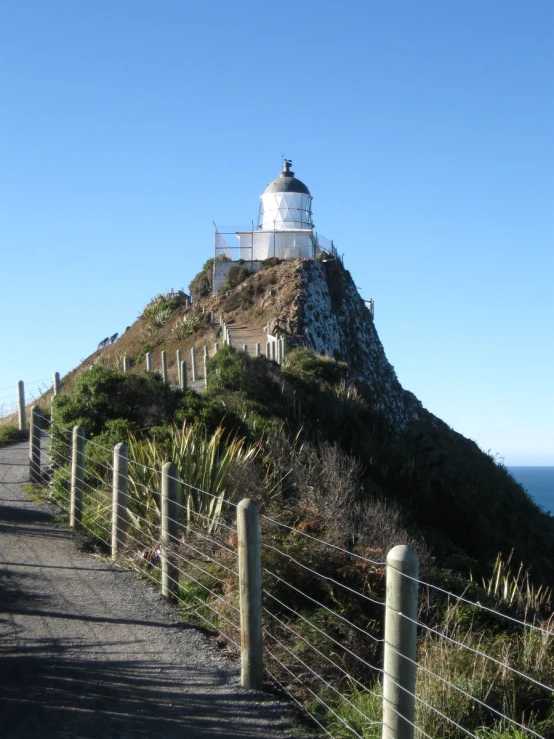 the lighthouse is visible through the wire fence