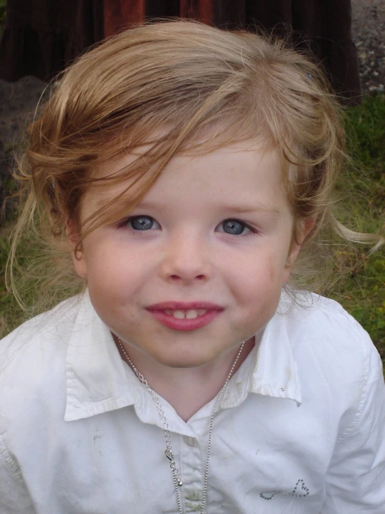 a  smiling for the camera with grass in the background