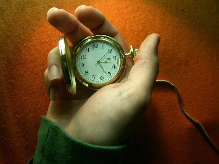 a hand holding a clock while on top of a table