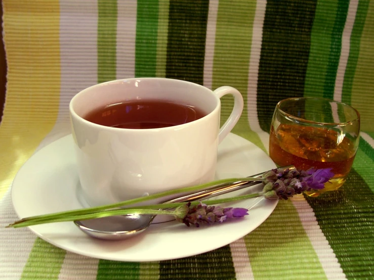 some flowers next to a tea cup with silverware on the plate