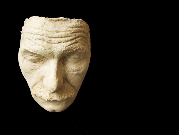 the face of a human is carved in white stone