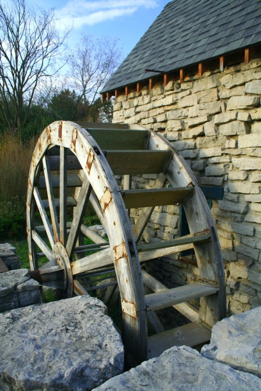 an old wooden spinning wheel in front of a stone house