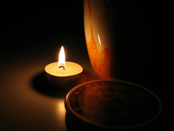 a lit candle sitting next to a bowl on a table