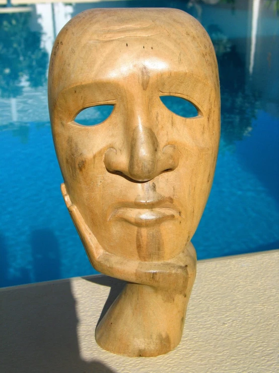 a wooden face sitting next to a swimming pool