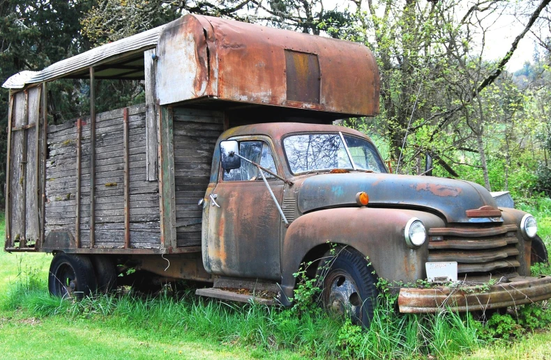 a old rusted truck parked in the grass