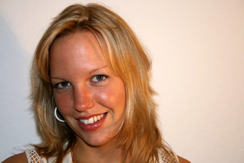 a woman smiles with big round earrings on her head