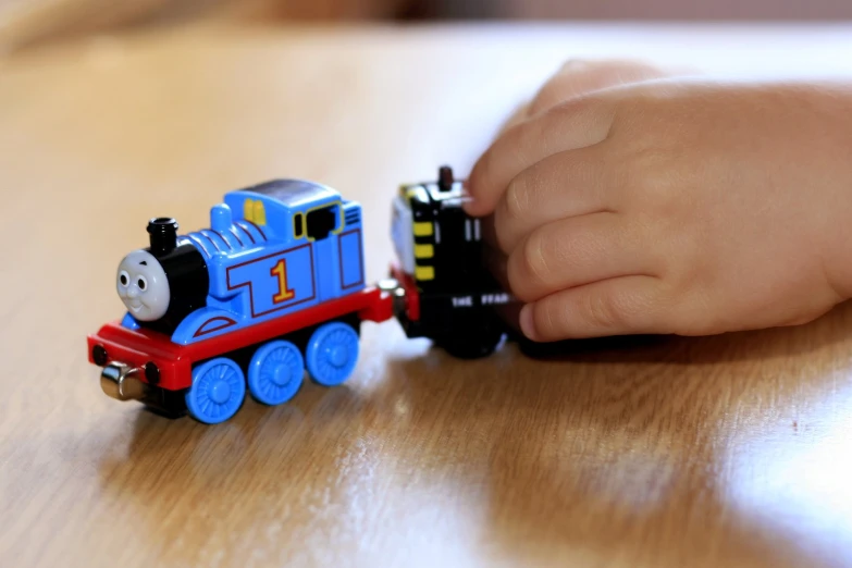 a hand holding a toy train on a table