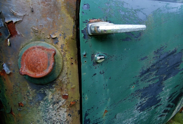 two old rusty door handles are on an green door