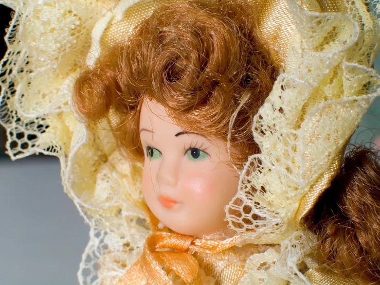 an antique doll wearing a bonnet with a golden ribbon
