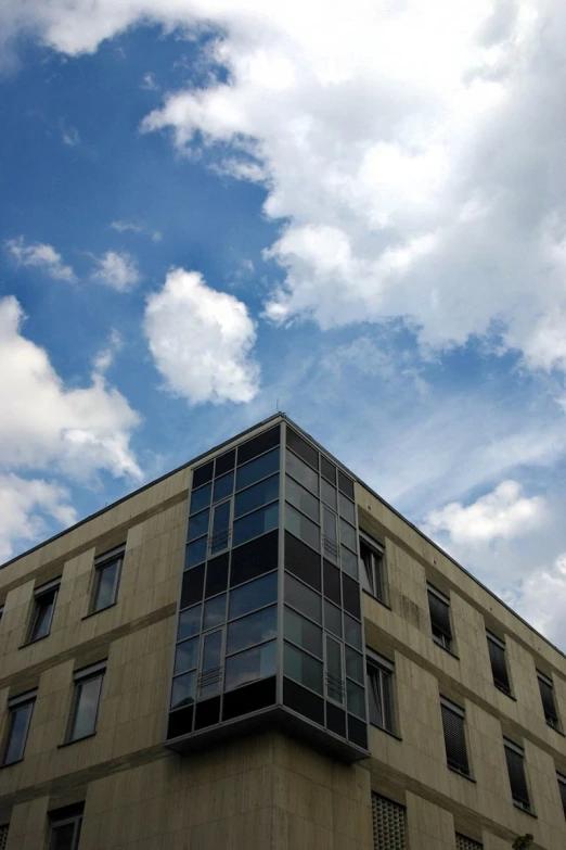 a gray building with black windows and a blue sky in the background