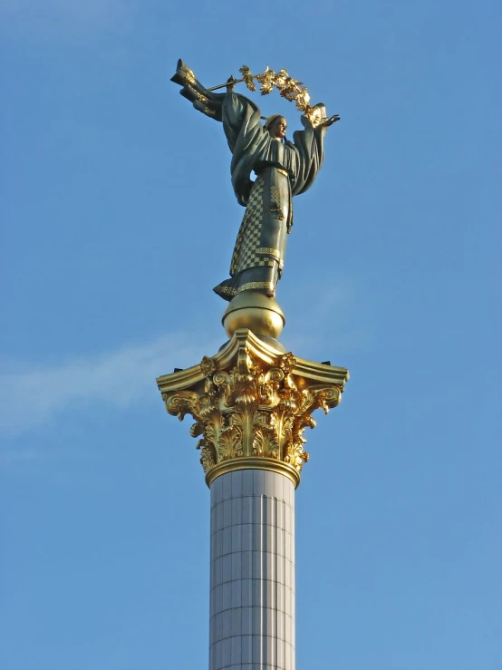 a statue atop a tall pillar in front of blue sky