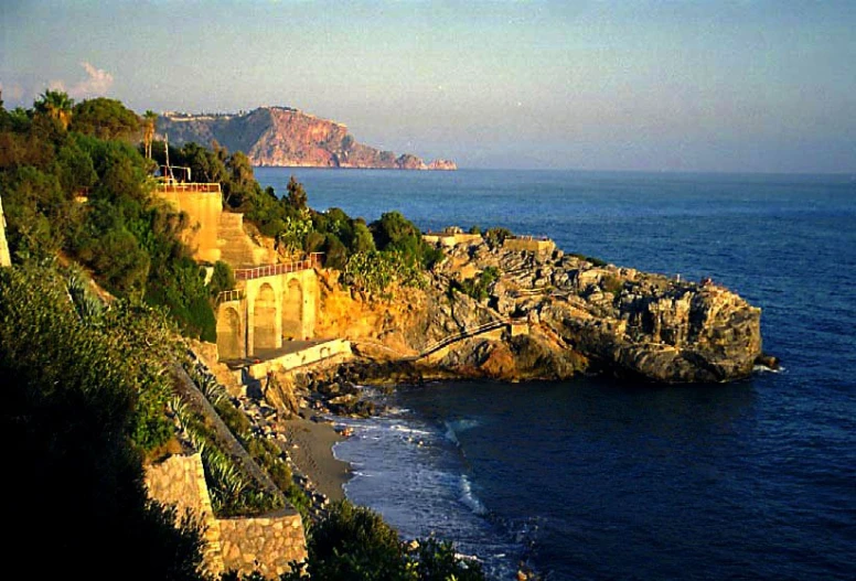 a cliff by the ocean that has stairs going up to it