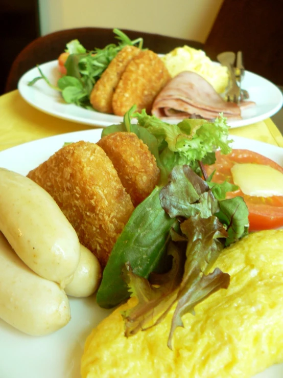 this plate contains food that includes eggs, salad and rolls