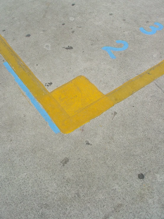 a yellow stop sign on concrete with blue letters