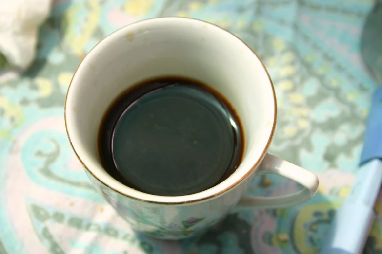 a cup of coffee sits on a paisley tablecloth
