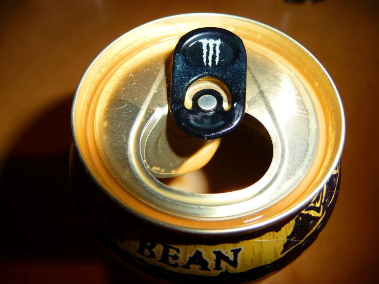a can of beer with its lid open and a black plastic cap on