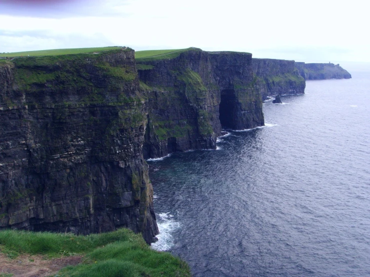 cliffs with grassy fields on top at the edge of a body of water