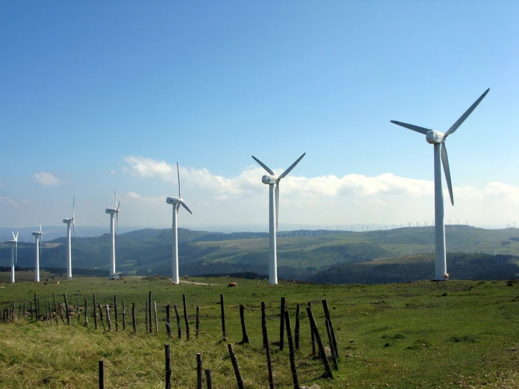 a field of windmills in a line on the hillside